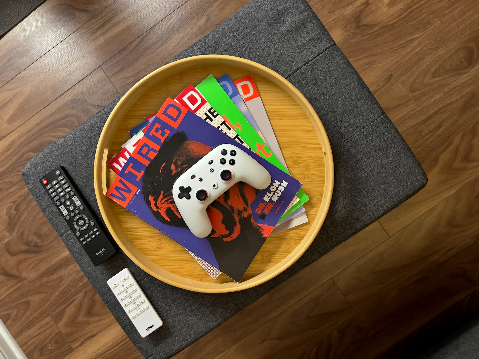 Stadia gaming controller on top of a some WIRED magazines on a round container placed on a table