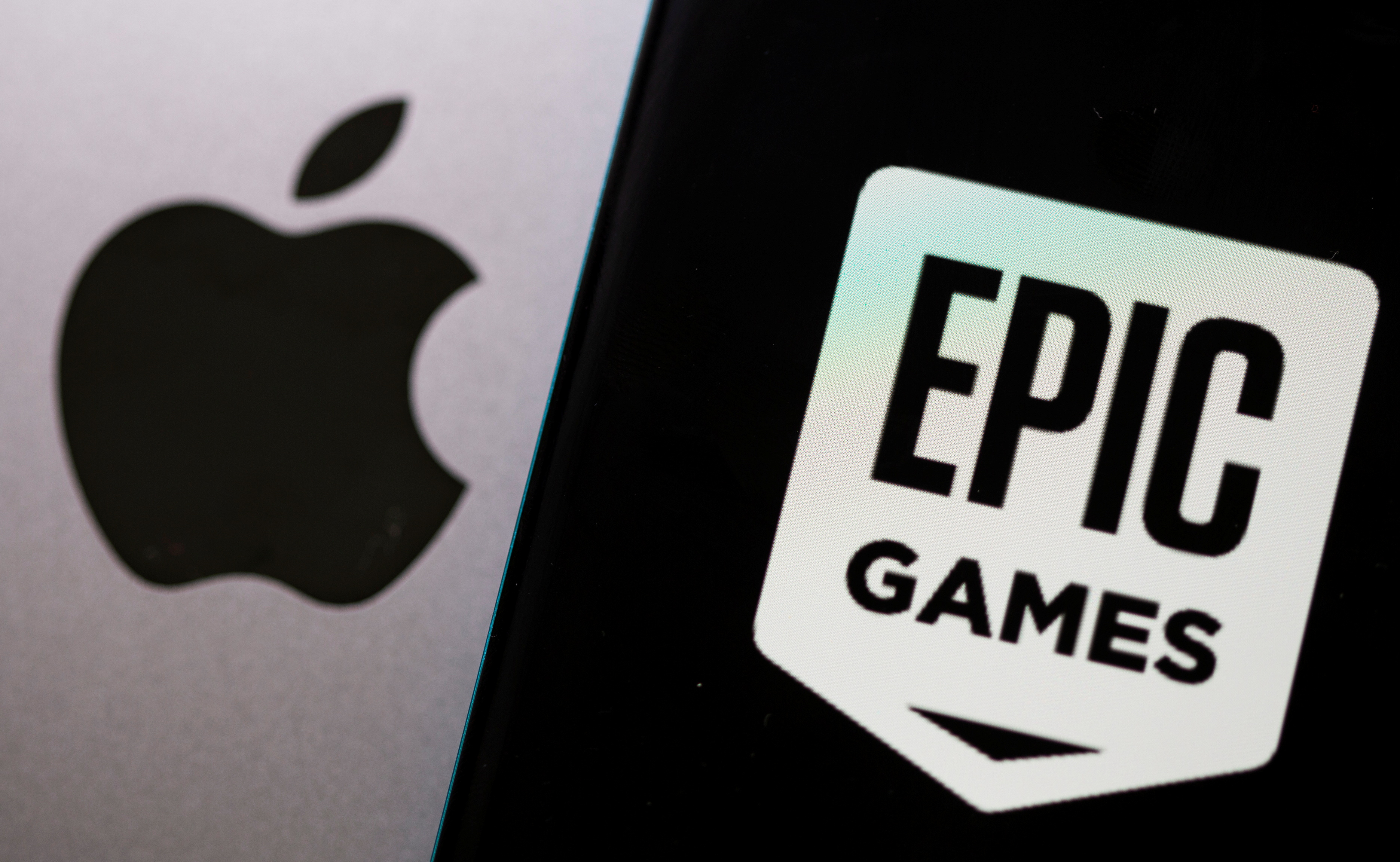 Smartphone with Epic Games logo is seen in front of Apple log.